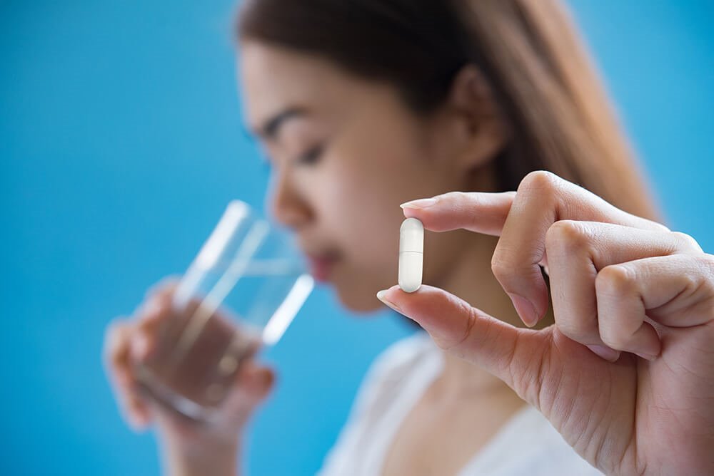 Woman taking a Parasi Cleaner capsule with a glass of water